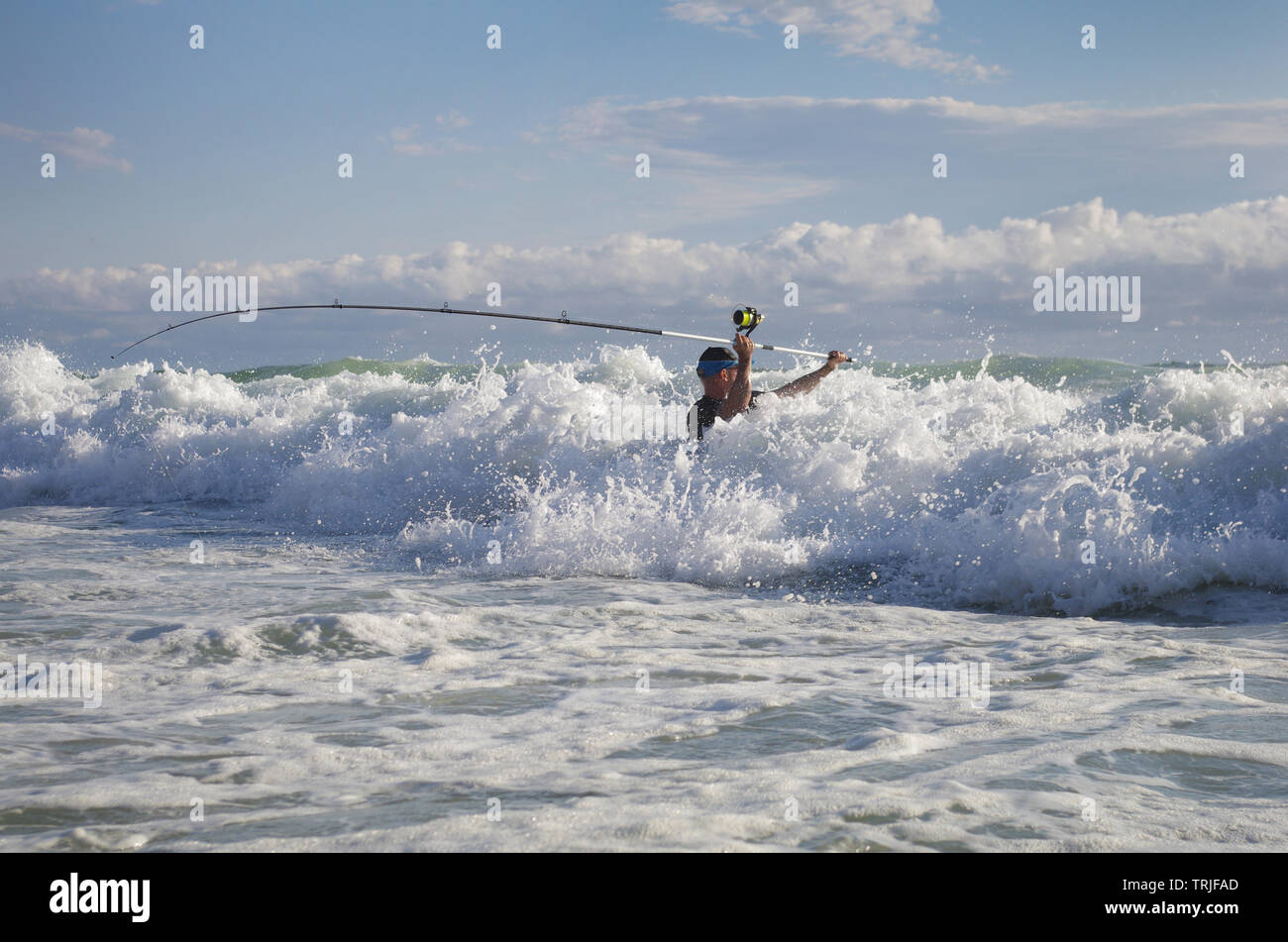 Surf Fischer in die Wellen versuchen, die Linie zu werfen. Angeln im Meer, Salzwasser Angeln Stockfoto