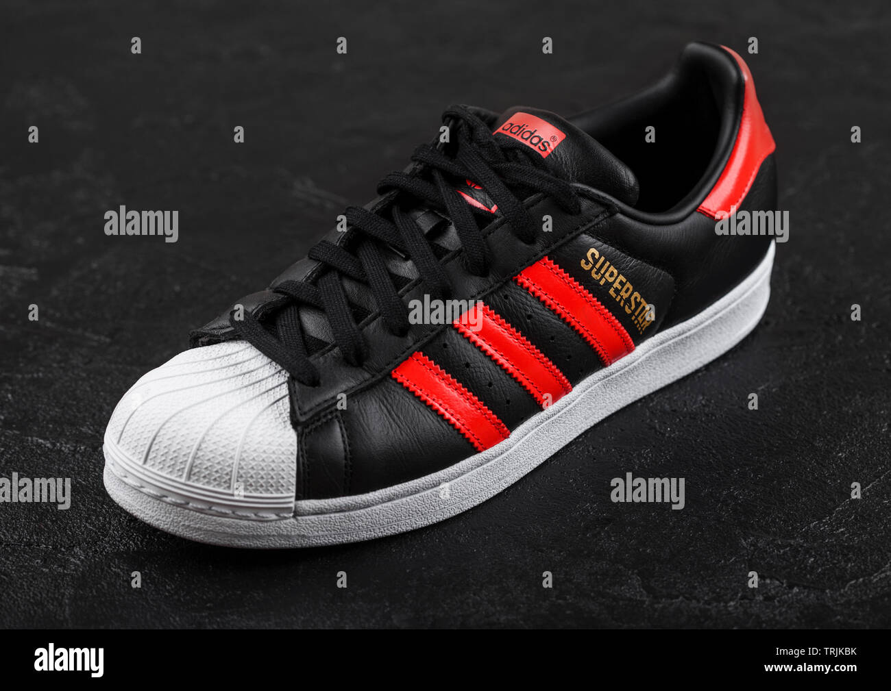 LONDON, UK - Juni 05, 2019: Adidas Superstar schwarz Schuh mit roten  Streifen auf schwarzem Hintergrund Stockfotografie - Alamy