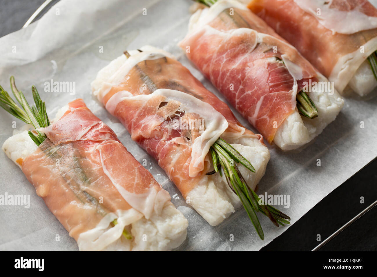 Vier Filets von Pollack Pollachius pollachius, dass in Zitronensaft und zerdrückten Knoblauch mariniert worden sein, bevor eingewickelt wurde in Parma Schinken mit Stockfoto