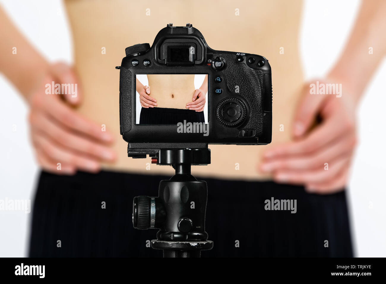 Fokus auf live view auf Kamera auf Stativ, Teenager, die Taille von der Diät Bild zurück Bild mit unscharfen Szene im Hintergrund. Teenage vlogg Stockfoto