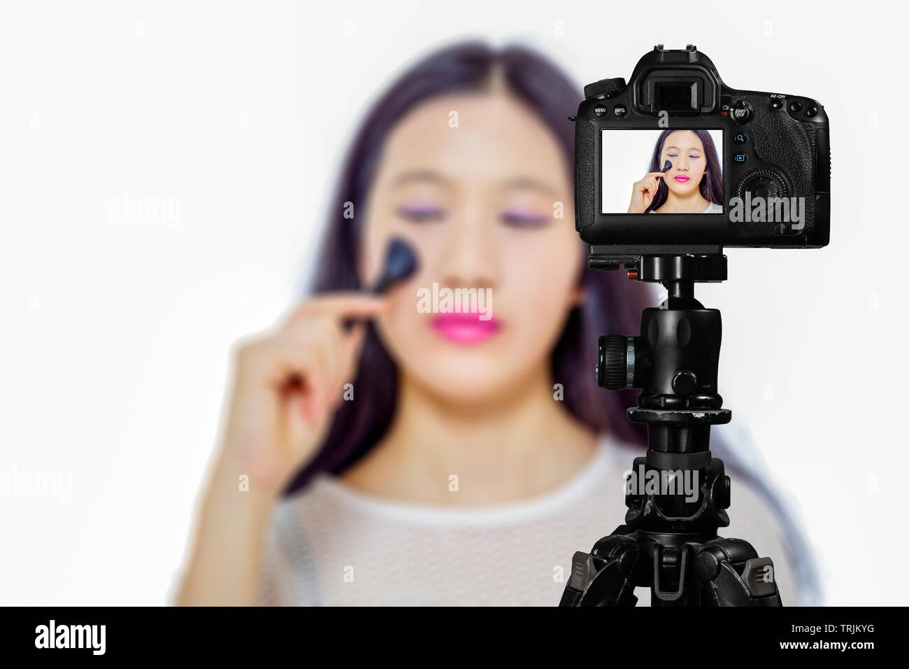 Fokus auf live view auf Kamera auf Stativ, junges Mädchen mit Kosmetik Bild zurück Bild mit unscharfen Szene im Hintergrund. Teenage vlogger livestrea Stockfoto