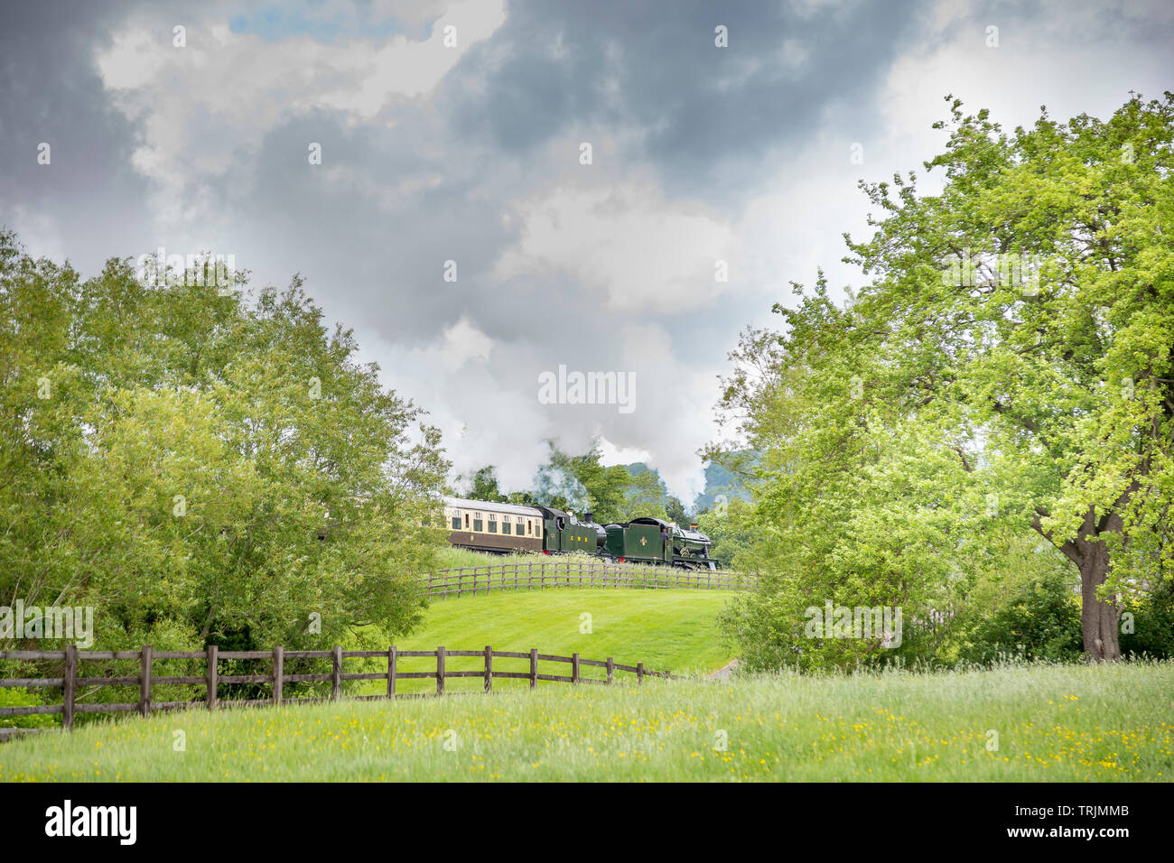 Seitenansicht des Vintage UK Dampfzug durch die englische Landschaft, puffing Dampf auf GWSR Erbe, sonnigen Nachmittag, aber dunkle Wolken über Stockfoto