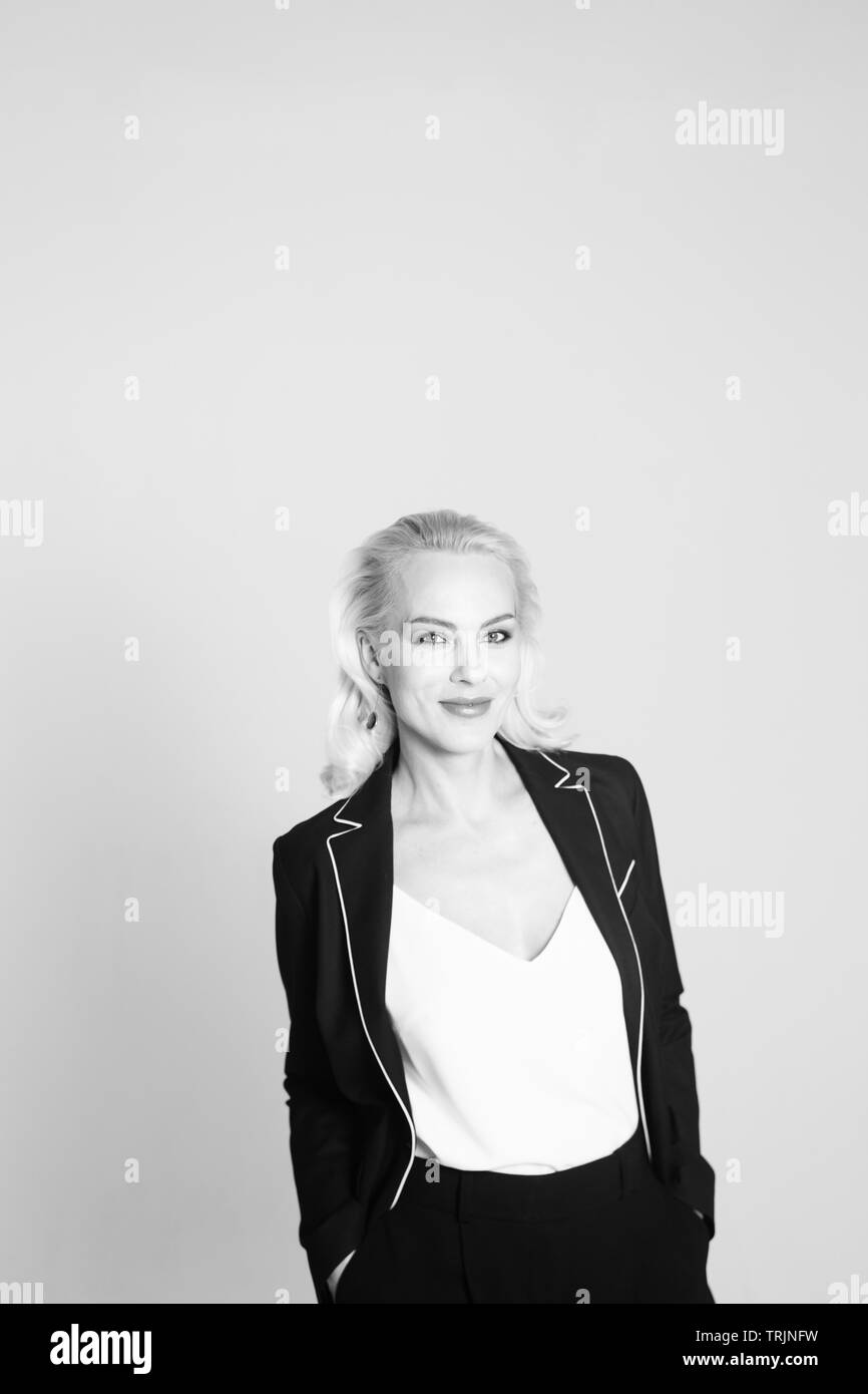 Studio Portrait von schöne blonde Frau in einem schwarzen Kleid gegen Weiße einfachen Hintergrund Stockfoto