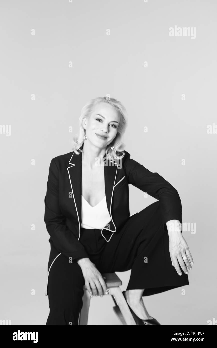 Studio Portrait von schöne blonde Frau in einem schwarzen Kleid gegen Weiße einfachen Hintergrund Stockfoto
