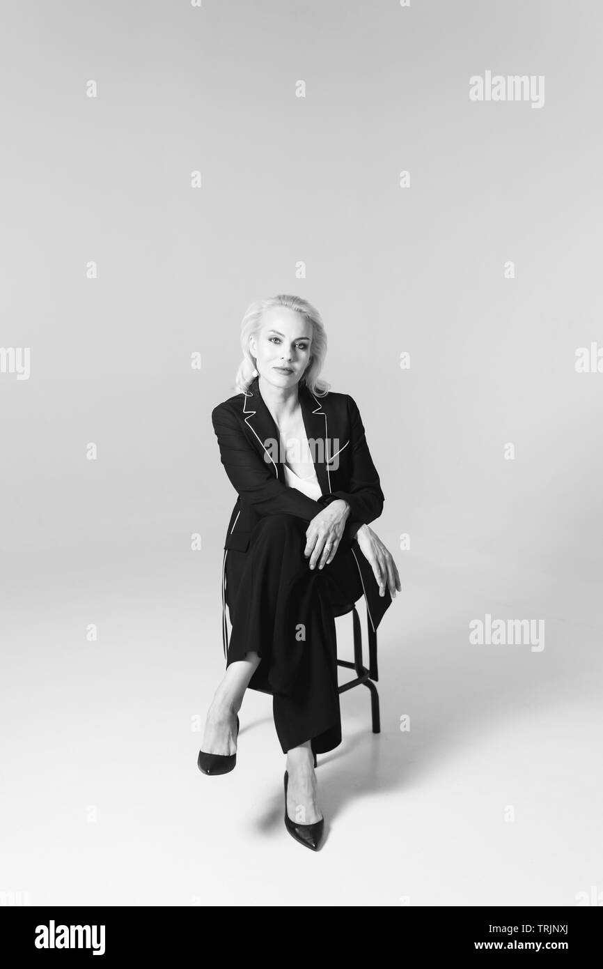 Studio Portrait von schöne blonde Frau in einem schwarzen Kleid gegen Weiße einfachen Hintergrund Stockfoto