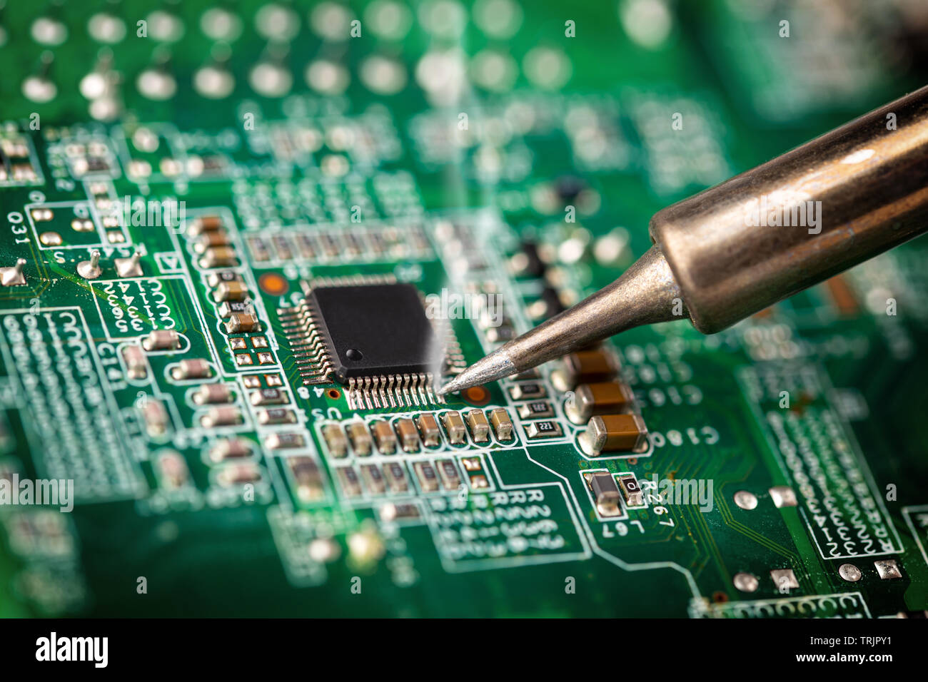 Löten einen Chip Prozessor mit Eisen auf einem grünen Circuit boad. Electroncs Service Technologie und macro Computer concept Hintergrund. Stockfoto