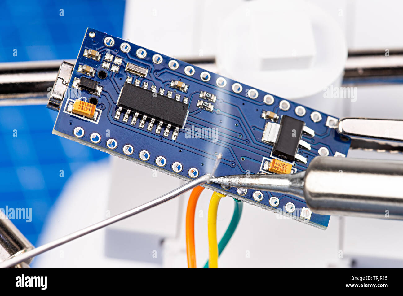 Löten Stifte und Drähte mit Eisen Werkzeug eines blau Micro Controller Chip board. Electroncs Service Technologie und Makro Hintergrund. Stockfoto