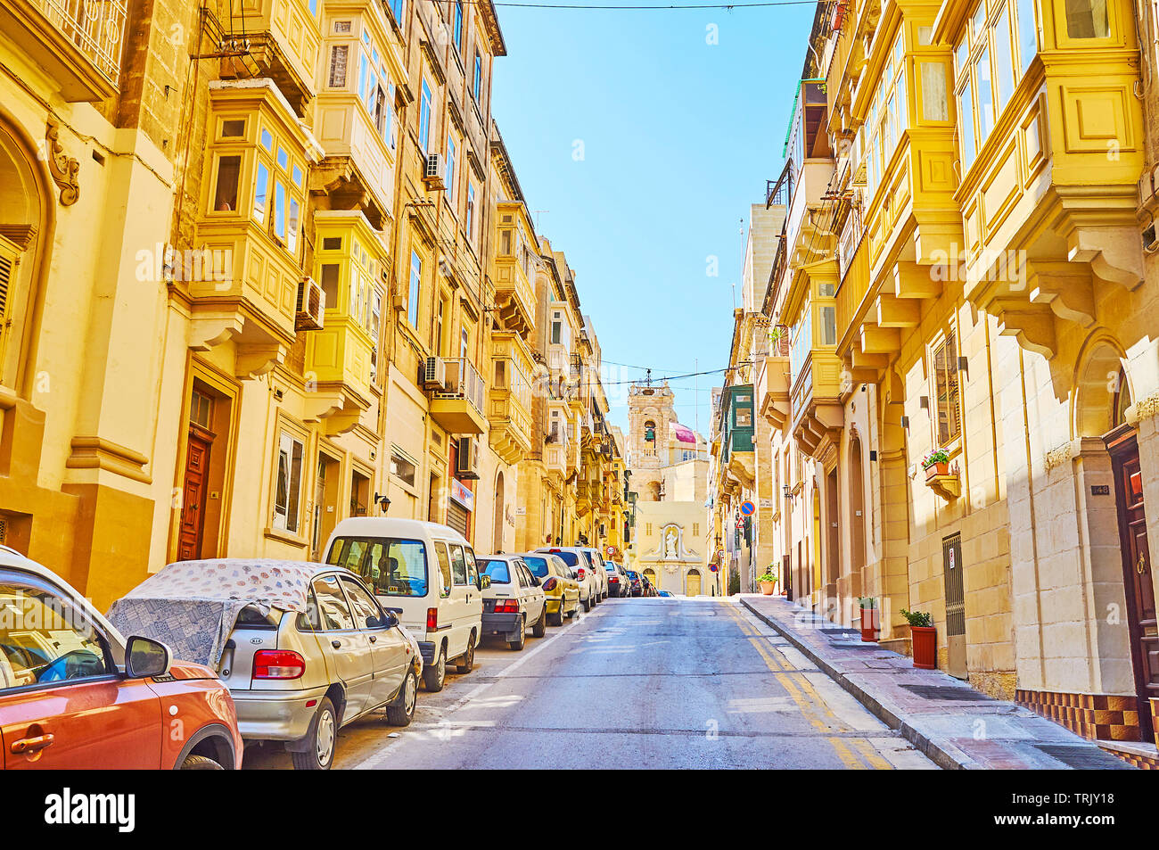 SENGLEA, MALTA - 19. JUNI 2018: Spaziergang auf den ruhigen Victoria Street mit Blick auf den traditionellen Wohn- bauten und den Glockenturm von St. Philip Kirche auf b Stockfoto