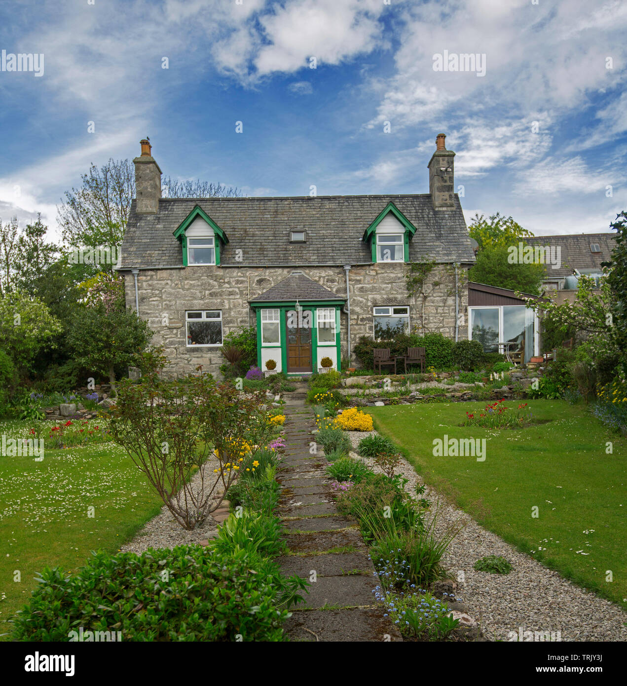 Malerische Landhaus aus Stein mit Weg durch bunte Garten und Rasen unter blauem Himmel in Schottland führenden Stockfoto