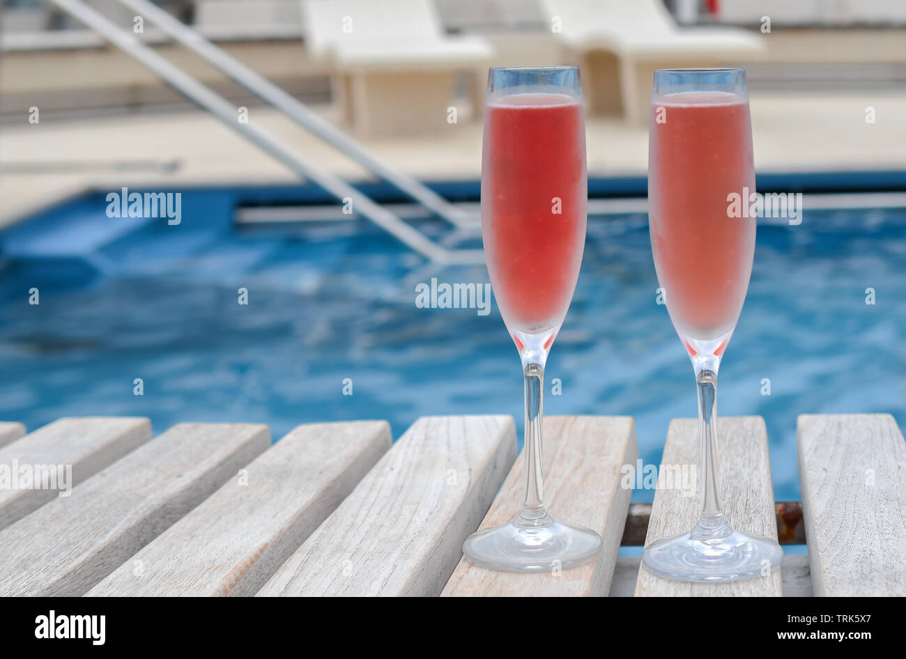 Ferienhäuser feier Konzept: Zwei Gläser mit rosa Champagner gefüllt. Schwimmbad von Kreuzfahrtschiff im Hintergrund. Stockfoto