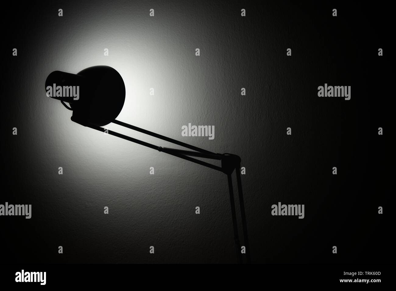 Tischleuchte, die eine dunkle Wand beleuchtet. Stockfoto