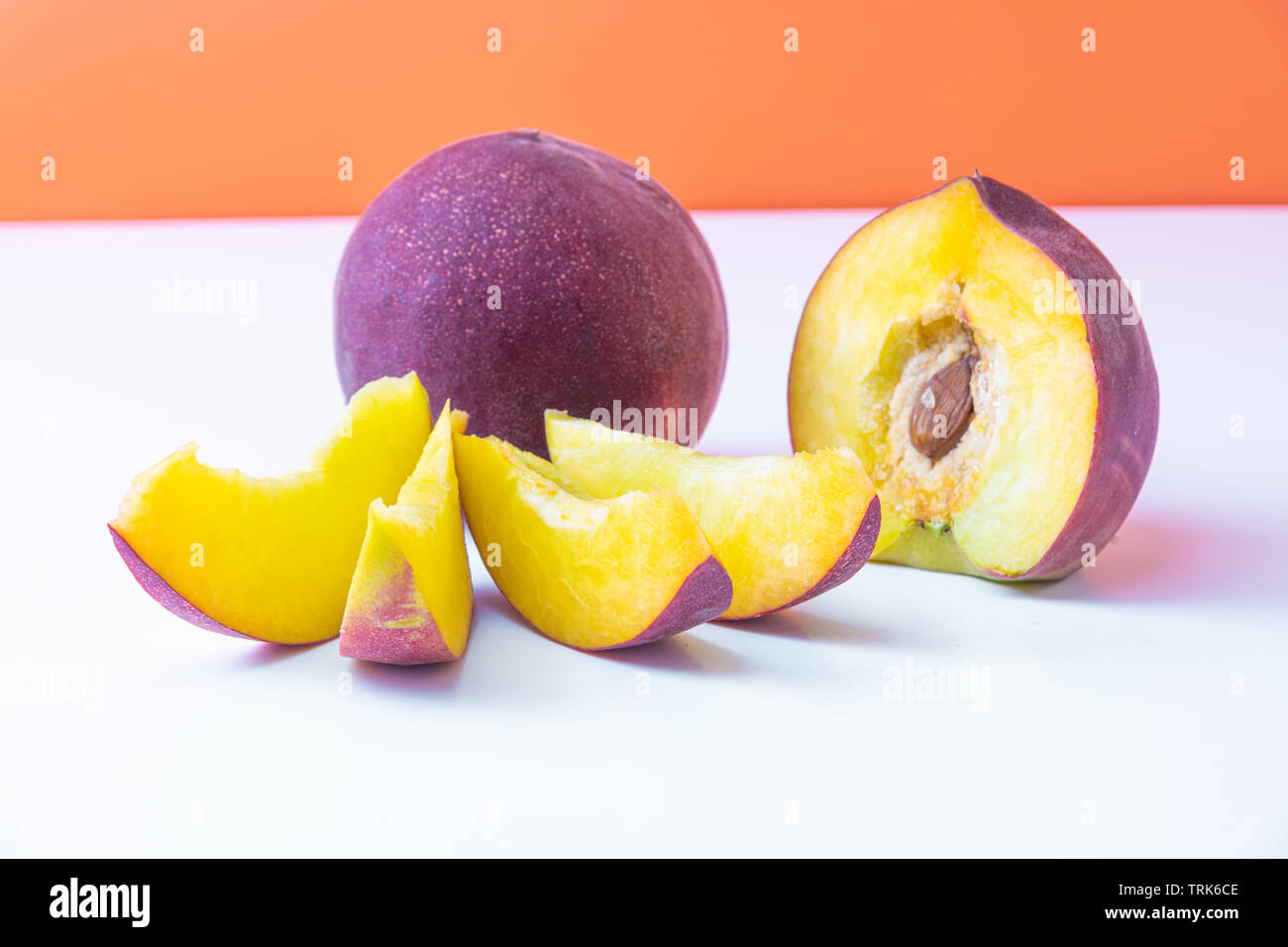Schöne elegante Komposition aus Reif saftig rot Nektarinen. Orange hinterlegt. Stockfoto