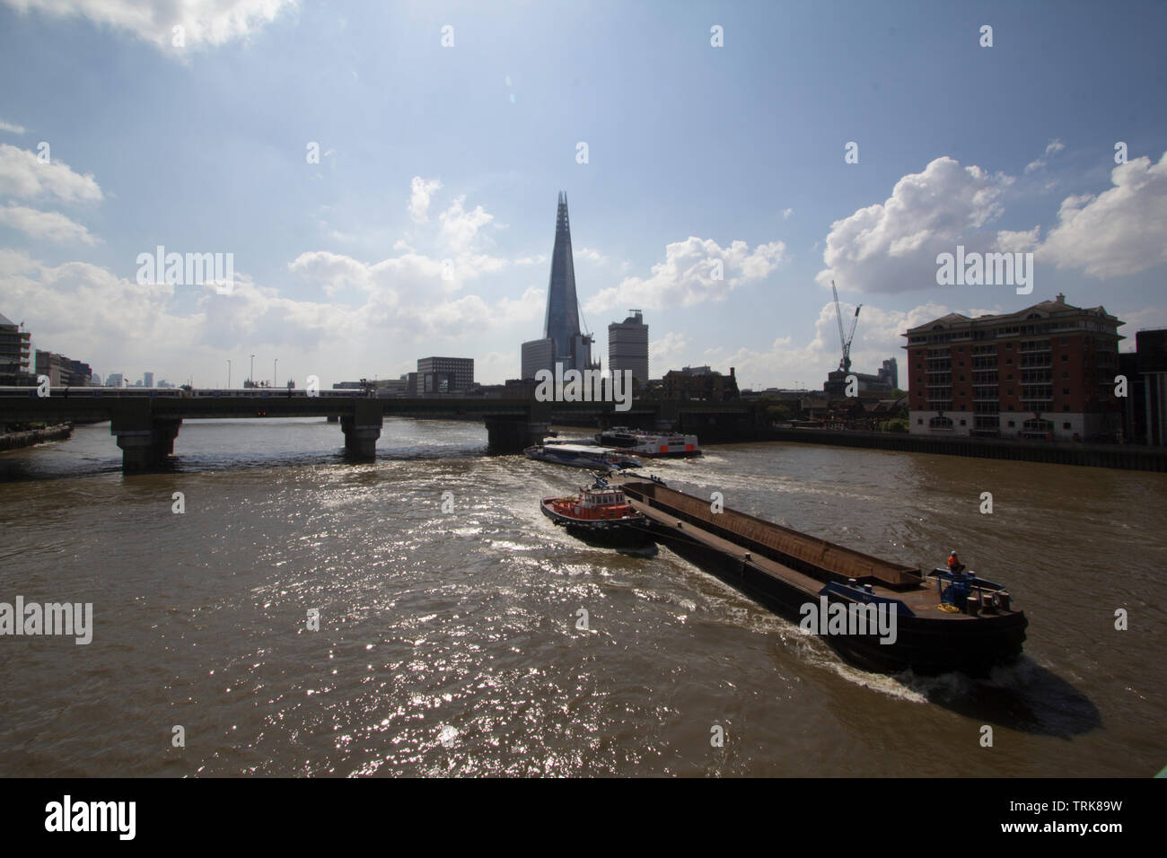 Barge, die Cory Umwelt, das größte Schiff auf der Themse, fließt zwischen Cannon Street Railway Bridge und die Southwark Bridge über die Themse, mit Schleppern und Shard im Hintergrund Stockfoto