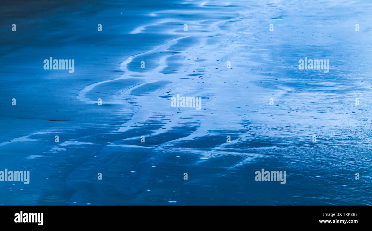 Wet Sand an der Küste. Abstrakt blau getönten Hintergrund Foto mit weichen selektiven Fokus Stockfoto