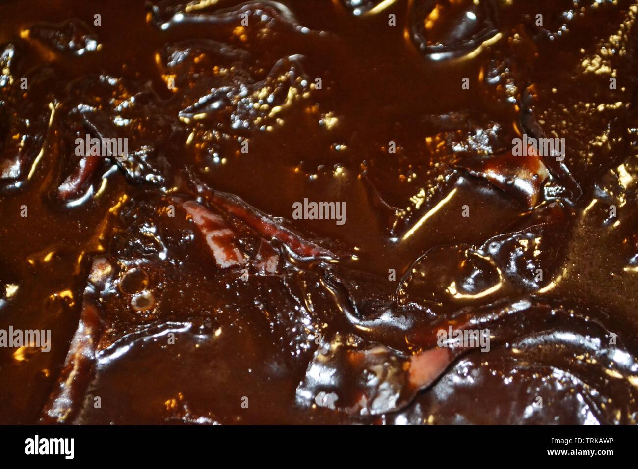Blur Hintergrund dunkel braune Flüssigkeit Oberfläche der Schokolade Apfelscheiben Wackelpudding. Stockfoto
