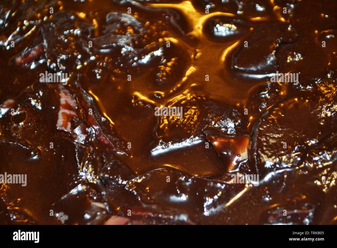 Blur Hintergrund dunkel braune Flüssigkeit Oberfläche der Schokolade Apfelscheiben Wackelpudding. Stockfoto