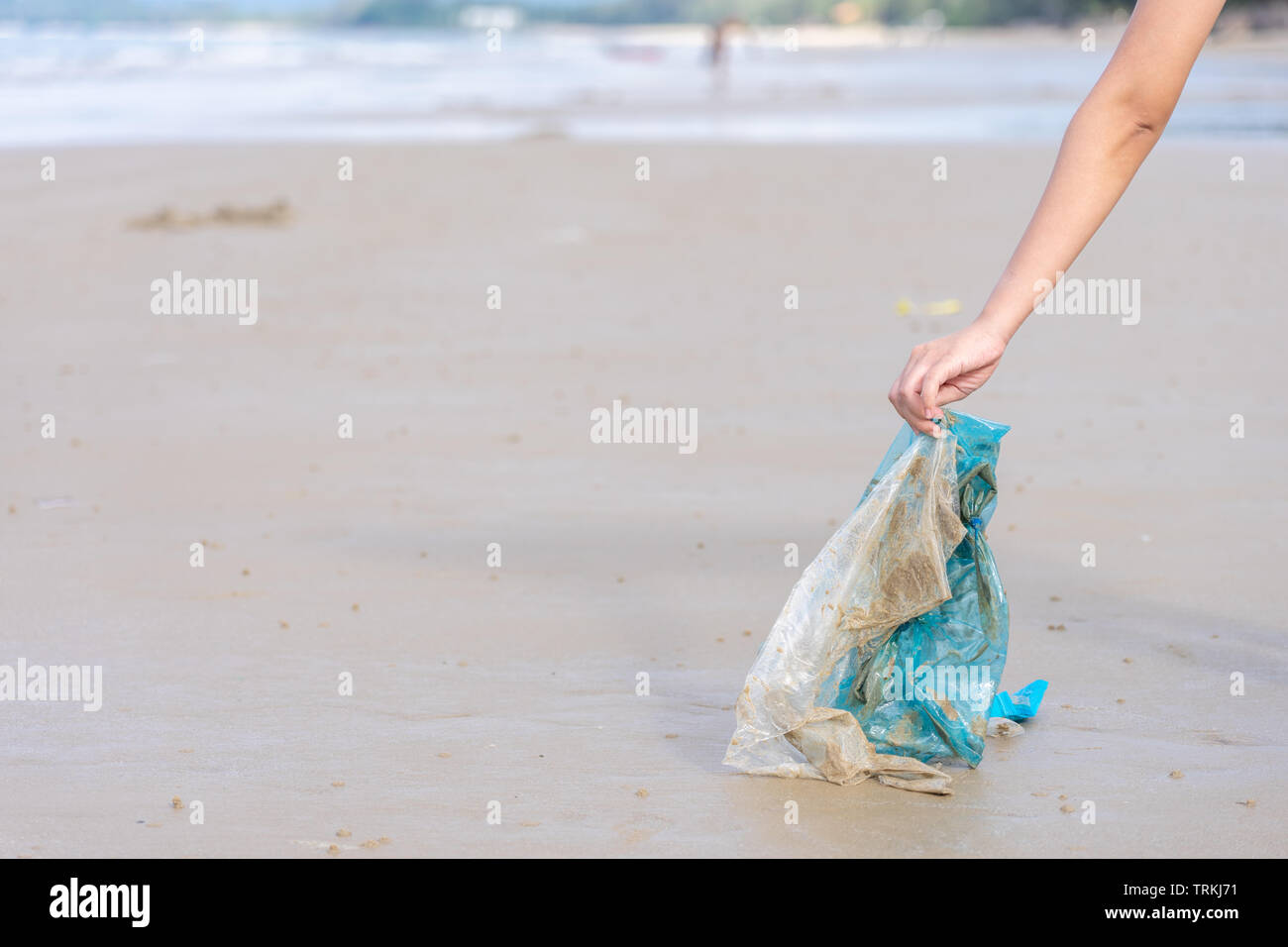 Woman's Hand herauf verwendet Plastikbeutel auf Sand Strand, Reinigung Seaside Beach. Umweltverschmutzung, ökologische Problem und Meeresverschmutzung con Stockfoto
