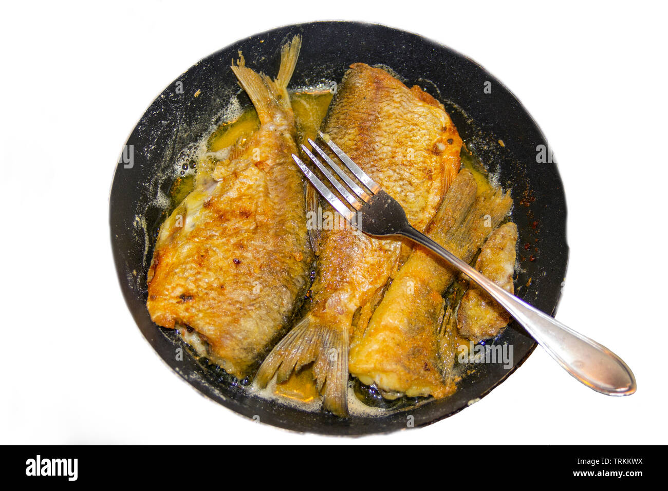 Das Foto der ganze gebratene Fische ohne Kopf auf der Pfanne oder Pfanne mit einer Gabel auf es Stockfoto