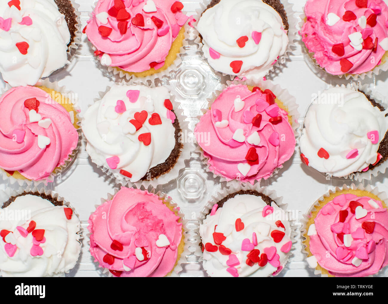 Ansicht von oben ordnet rosa und weisse Glasur Sahne Cupcakes mit Herzen verziert besprüht Stockfoto