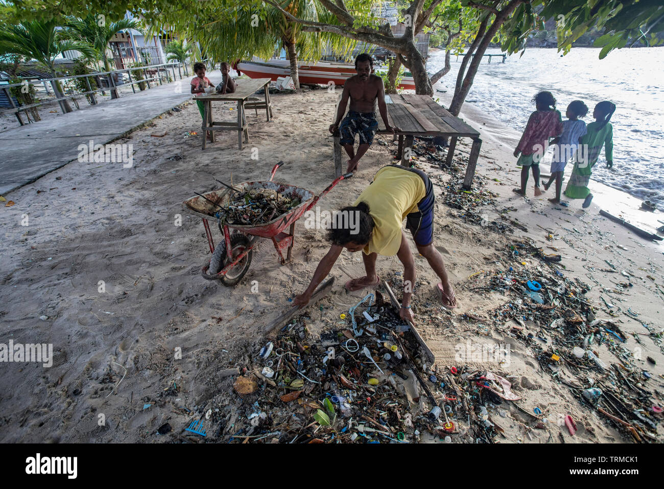 Insel Papua Dorfbewohner Clearing bis Kunststoff marine Müll am Strand an einem windigen Tag gedumpten in Manyaifun auf der Insel Batang Pele, West Stockfoto