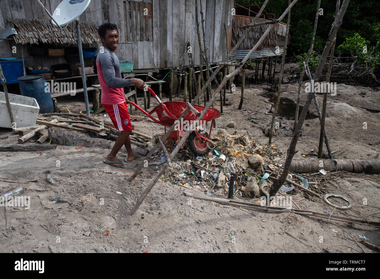 Papua Mann dumping Kunststoff marine Müll am Strand in Manyaifun während einer windigen Tag gesammelt auf der Insel Batang Pele, West Waigeo, Raja Amp Stockfoto