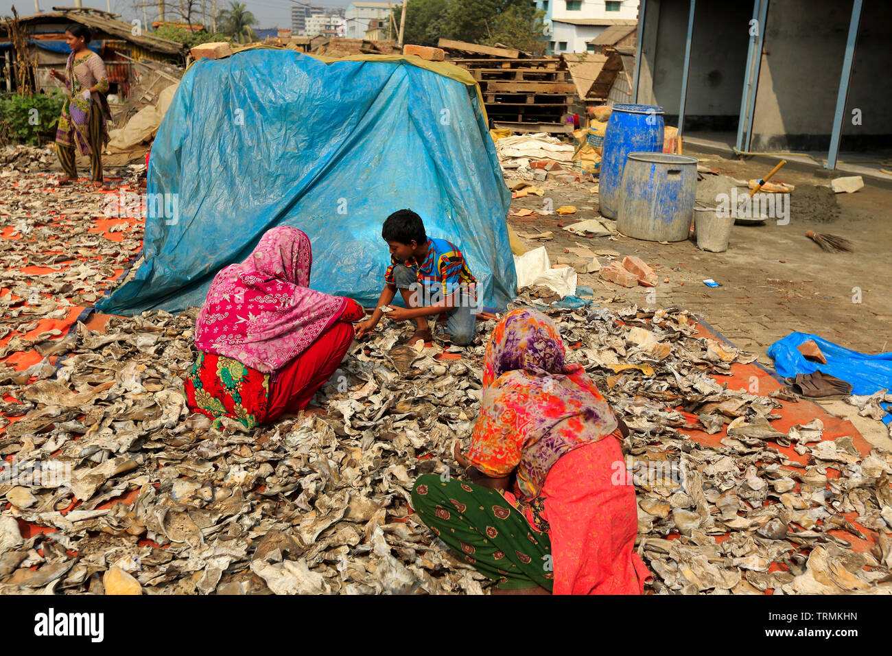 Frauen, die ein Kind Felle an der Bank von buriganga Fluss in Hazaribag zu trocknen. Dhaka, Bangladesch. Stockfoto