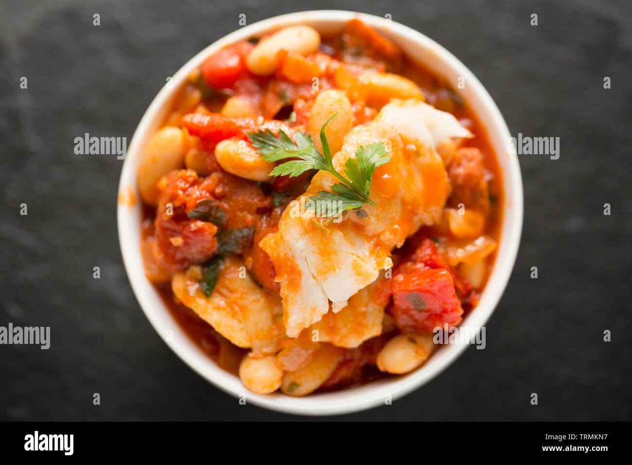 Ein Pollack und Chorizo Wurst fisch Eintopf mit Tomaten, geröstete Paprika, Tomaten aus der Dose, gehackte Zwiebeln, cannellini Bohnen und Petersilie. T Stockfoto