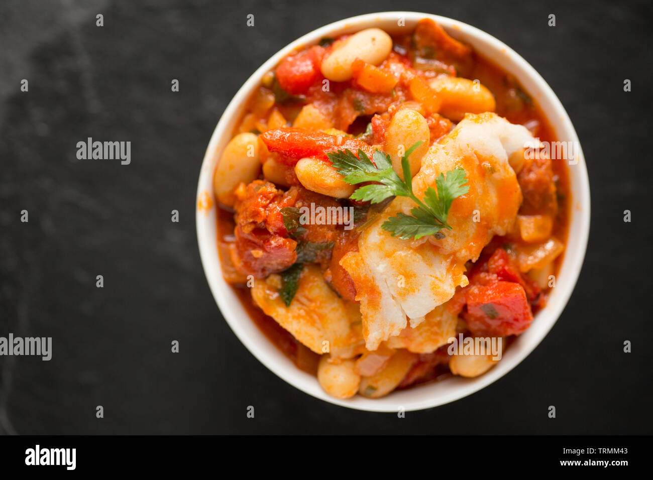 Ein Pollack und Chorizo Wurst fisch Eintopf mit Tomaten, geröstete Paprika, Tomaten aus der Dose, gehackte Zwiebeln, cannellini Bohnen und Petersilie. T Stockfoto