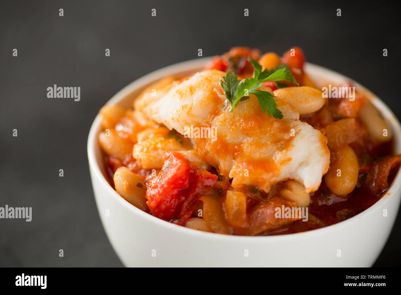 Ein Pollack und Chorizo Wurst fisch Eintopf mit Tomaten, geröstete Paprika, Tomaten aus der Dose, gehackte Zwiebeln, cannellini Bohnen und Petersilie. T Stockfoto