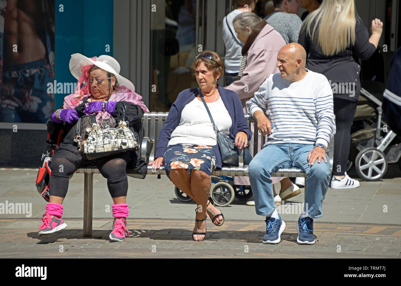 Bizarr lady sitzt auf der Bank mit ein paar gekleidet Stockfoto