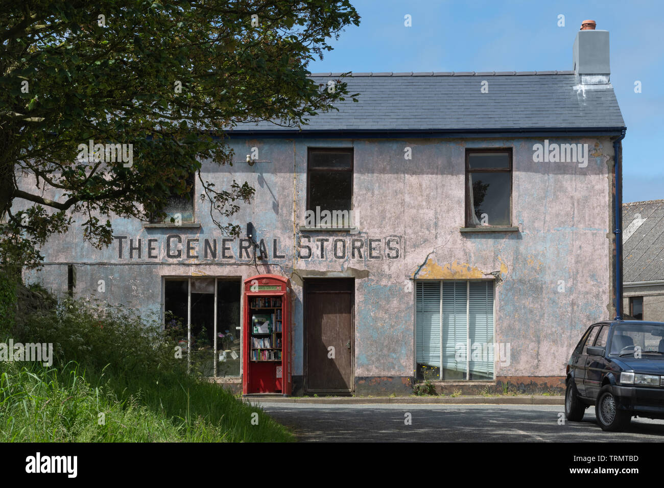 Äußere des verfallenen Allgemeine Speicher Dorfladen in Mathry, Pembrokeshire, Großbritannien mit einem Ausgedienten rote Telefonzelle, jetzt eine Community Library Stockfoto