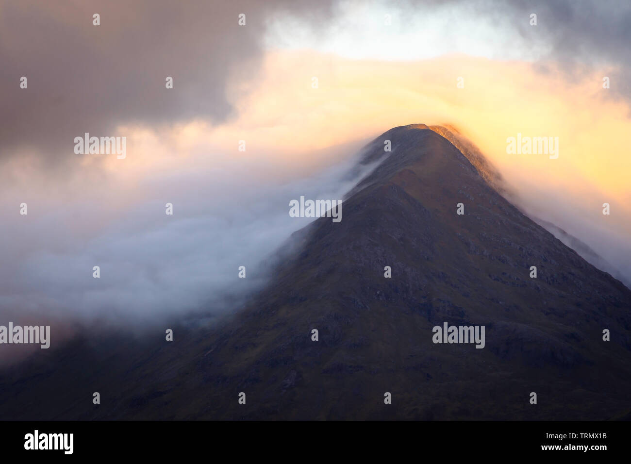 First Light kissing Berg bei Sonnenaufgang und Cloud Inversion in Tal. majestätische Landschaft der schottischen Highlands. schönen Morgen Szene in Glencoe. Stockfoto