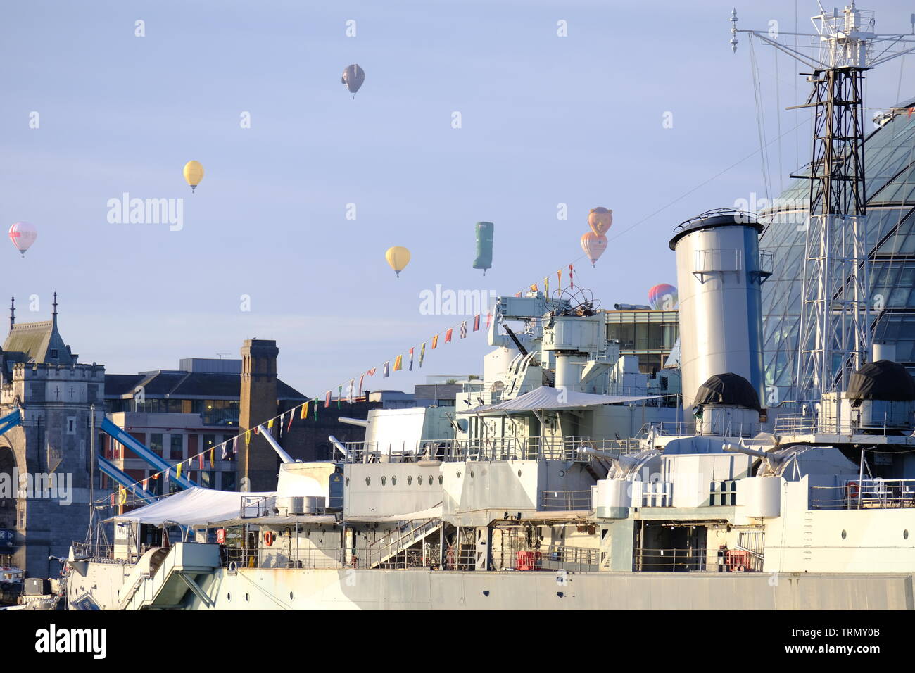 Die floatilla von der RICOH Oberbürgermeister von London's Hot Air Balloon Regatta 2019 führt über HMS Belfast und der Tower Bridge Während am frühen Morgen. Stockfoto