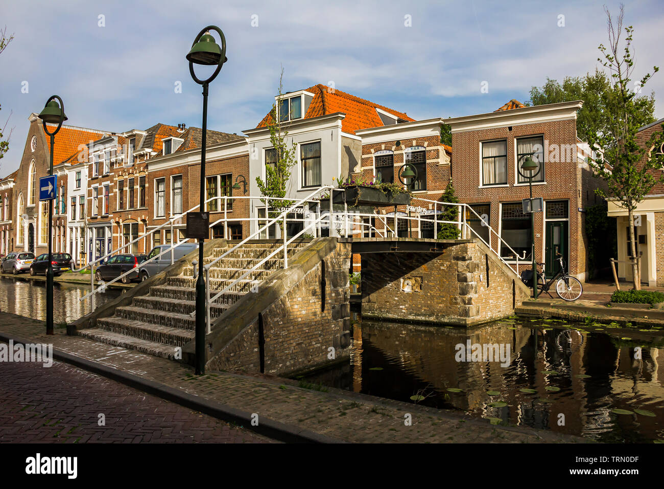 Gouda, Holland, Niederlande, April 23, 2019, Fahrräder in der Nähe einer Brücke in einer Straße geparkt in Gouda Altstadt. Blumen (Tulpen) auf den Vordergrund in einem Flow Stockfoto