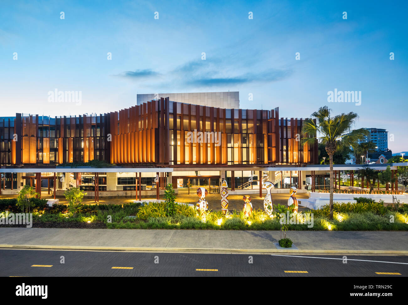 Die Fassade der Cairns Performing Arts Center in der Dämmerung beleuchtet. Eine Reihe von "bagu "heimischen Skulpturen sitzen an der Vorderseite des Zentrums. Cairn Stockfoto