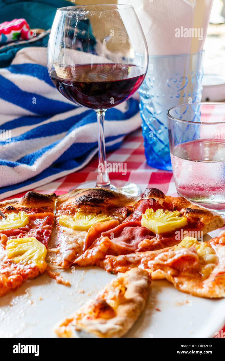Ein Glas Wein und Pizza auf einen Esstisch. Stockfoto