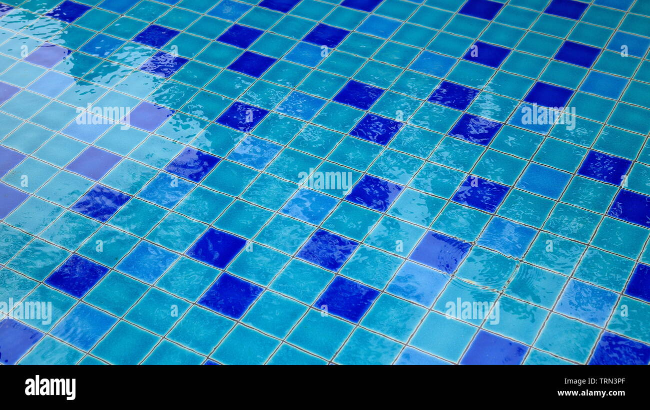 Schwimmbad keramische Fliesen in klares Wasser bedeckt. hellblau Fliesen übersät mit blauen Kacheln in einem regelmäßigen Muster Design. Freizeit pool Design. Stockfoto