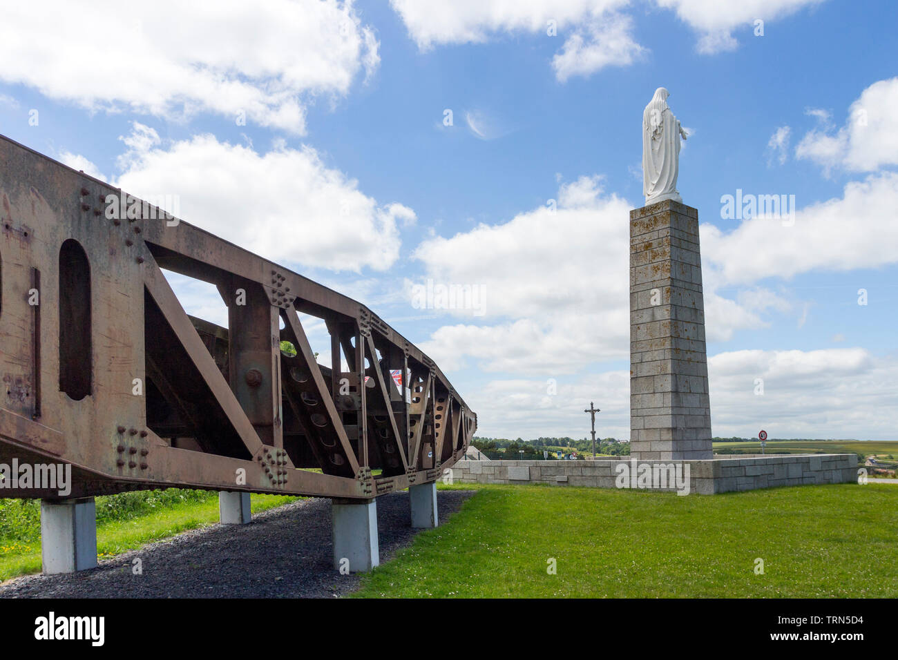 Teile der Maulbeere Hafen an der Royal Engineers Kriegerdenkmal mit Statue der Jungfrau Maria mit Blick auf D-Day Strände von Arromanches-les-Bains Stockfoto