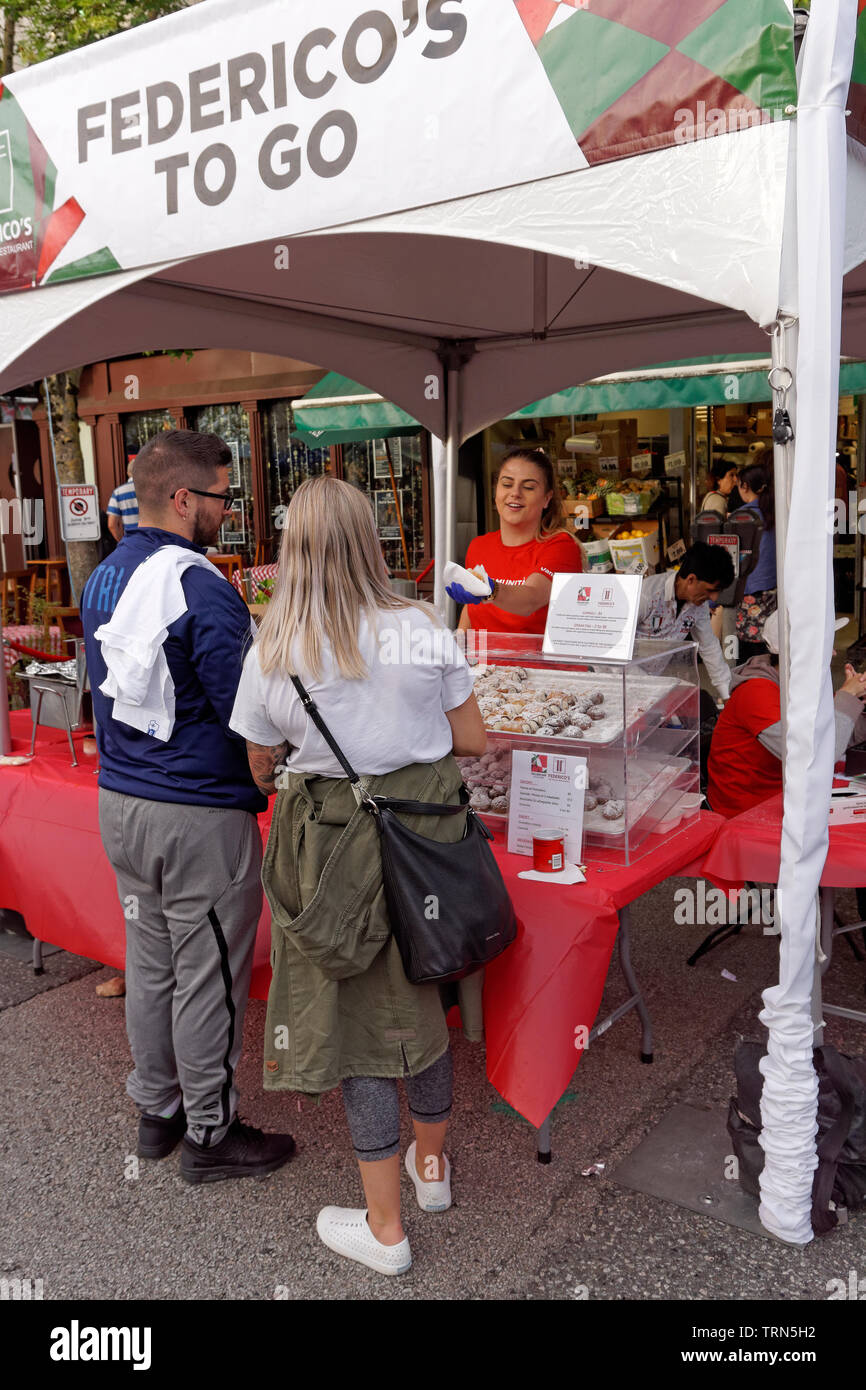 VANCOUVER, BRITISH COLUMBIA, KANADA - 9. JUNI 2019. Ein junger Frauen Lebensmittel Hersteller cannoli den Kunden am 2019 Italienischer Tag Festival auf Commercial Drive in Vancouver's Viertel Little Italy. Italienischer Tag ist das größte jährliche kulturelle Street Festival. Stockfoto