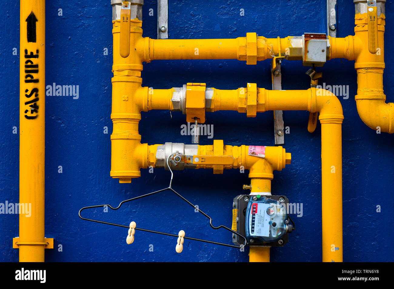 Blaue Wand mit gelben Gasleitungen Stockfoto