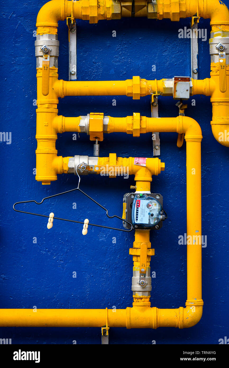 Blaue Wand mit gelben Gasleitungen Stockfoto