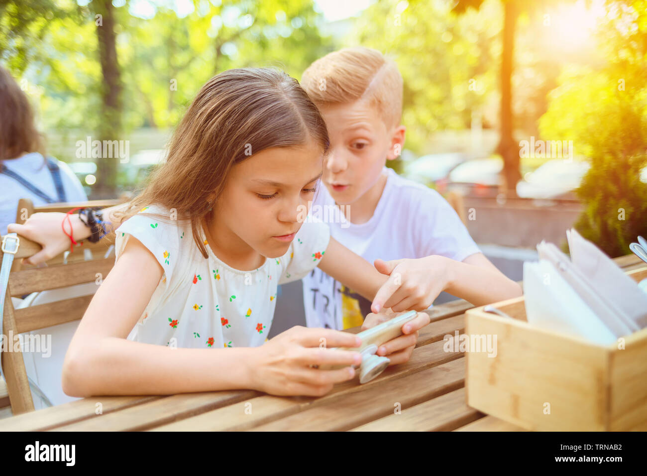 Kinder spielen mit Handy, Terrasse, süchtig nach Gadget Stockfoto