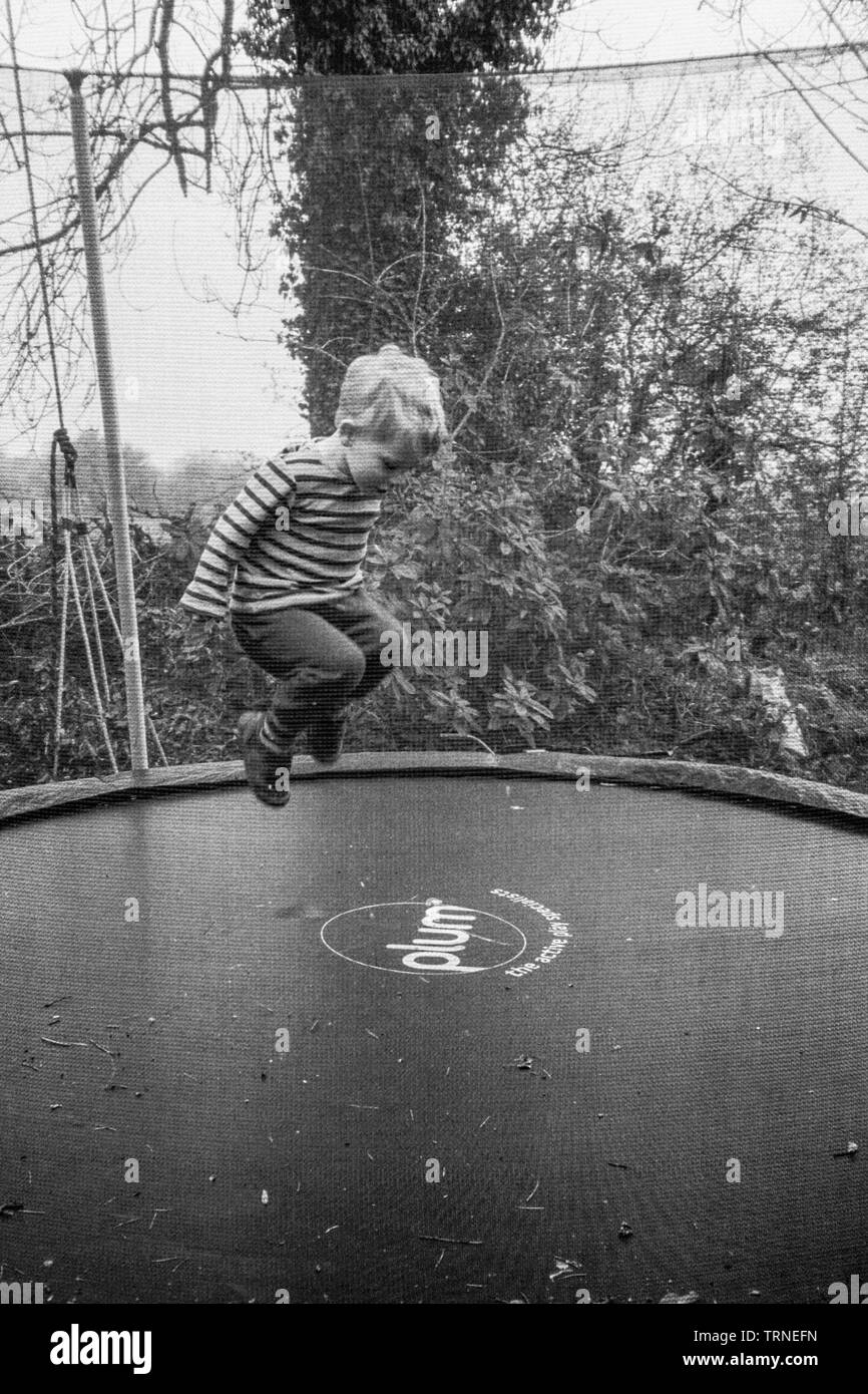 Zwei Jahre alten Jungen Hüpfen auf einem Garten Trampolin, Medstead, Alton, Hmapshire, England, Vereinigtes Königreich. Stockfoto