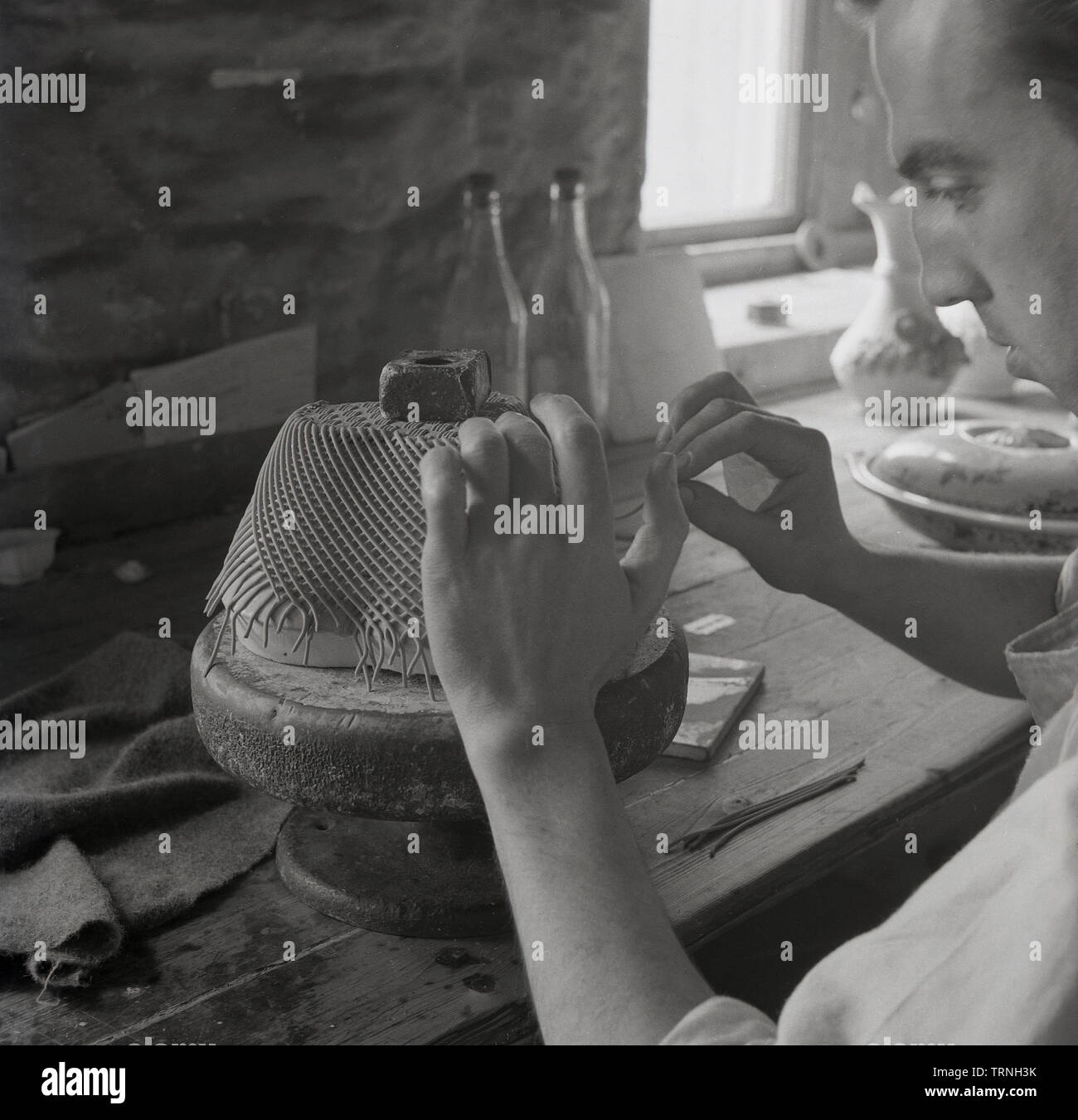 1950, historische, männliche Handwerker arbeiten an einem Stück Keramik Kunst in eine Töpferei, England, UK. Stockfoto