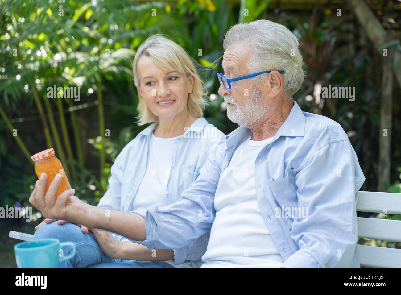 Alte Mann und eine Brille zum Lesen von kleinen Labels auf Konfitüre-gläser. Konzept der Vision.- Bild Stockfoto