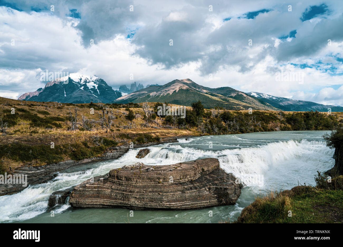 Die 3 Türme und Gebirge von Torres del Paine National Park eine dramatische Kulisse für die sprudelnden Paine Wasserfall hinzufügen im Vordergrund. Stockfoto