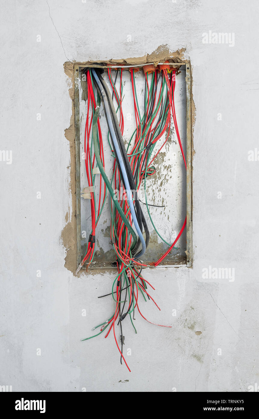 Elektrische Drähte eines energiepolitischen Rahmenprogramms von einem Haus im Bau. Freiliegende Kabel, Energie Kasten an der Wand. Stockfoto