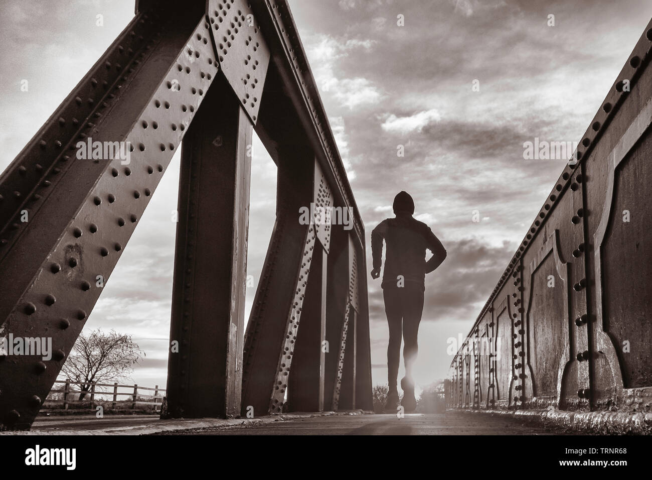 Rückansicht des Menschen über die Brücke bei Sonnenaufgang. Großbritannien Stockfoto