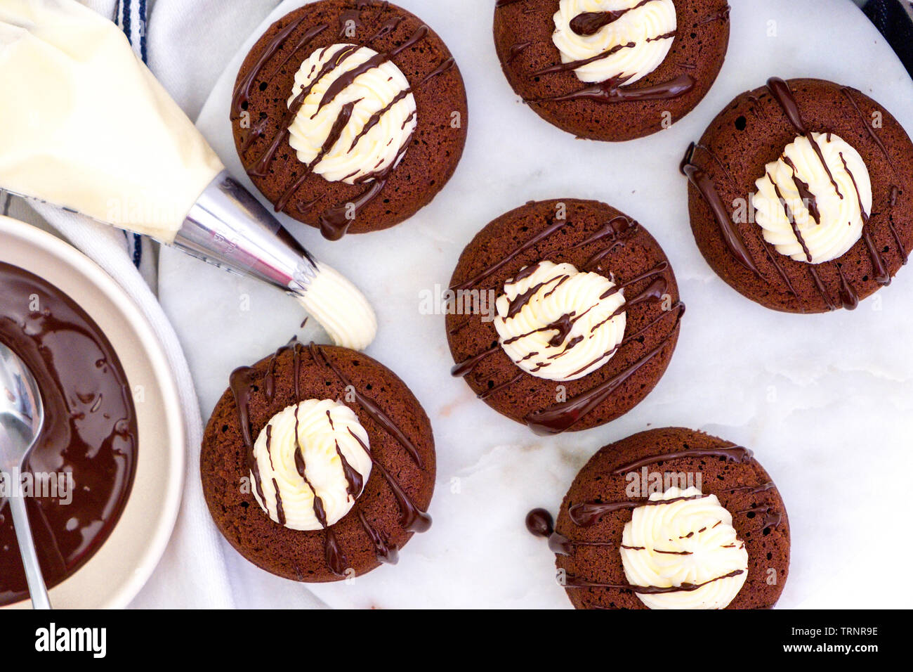 Ansicht von oben Flach von sechs Schokolade Donuts mit weißem Zuckerguss und beträufelt mit geschmolzener Schokolade, sitzen auf einer Marmorplatte Stockfoto