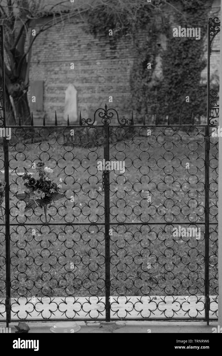 Schmiedeeisernes Tor mit der Blume Symbole auf dem Friedhof von Cremona. Schwarz und Weiß Stockfoto